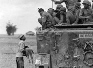 A Vietnamese farmer holds the body of his dead child while a group of South Vietnamese soldiers looks on.  Photo: Horst Faas. 